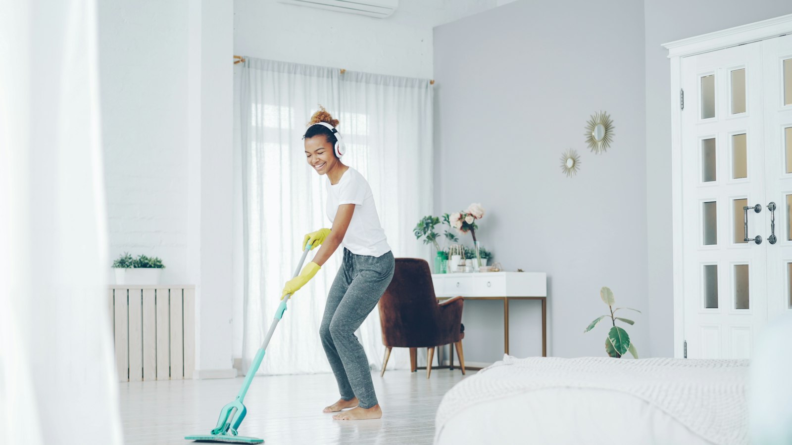 A cleaner happily mopping a bright, sunlit room